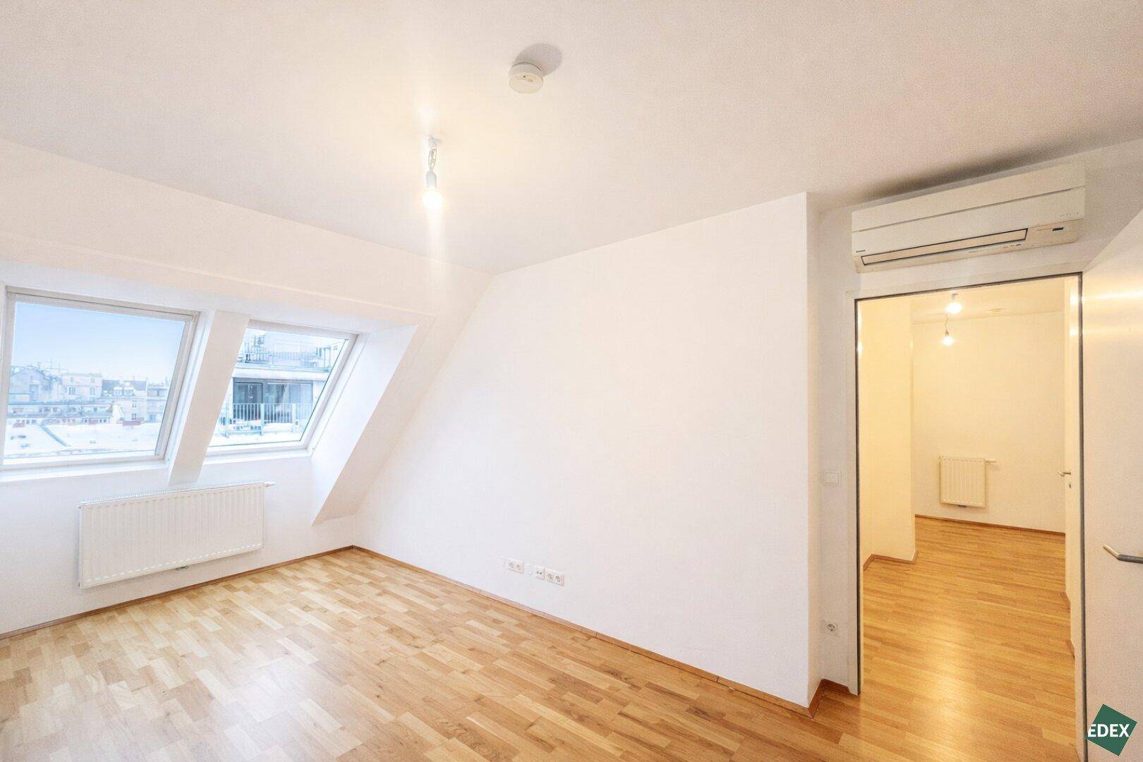 Schlafzimmer im Dachgeschoss mit Holzfußboden, Dachfenstern und Klimaanlage.