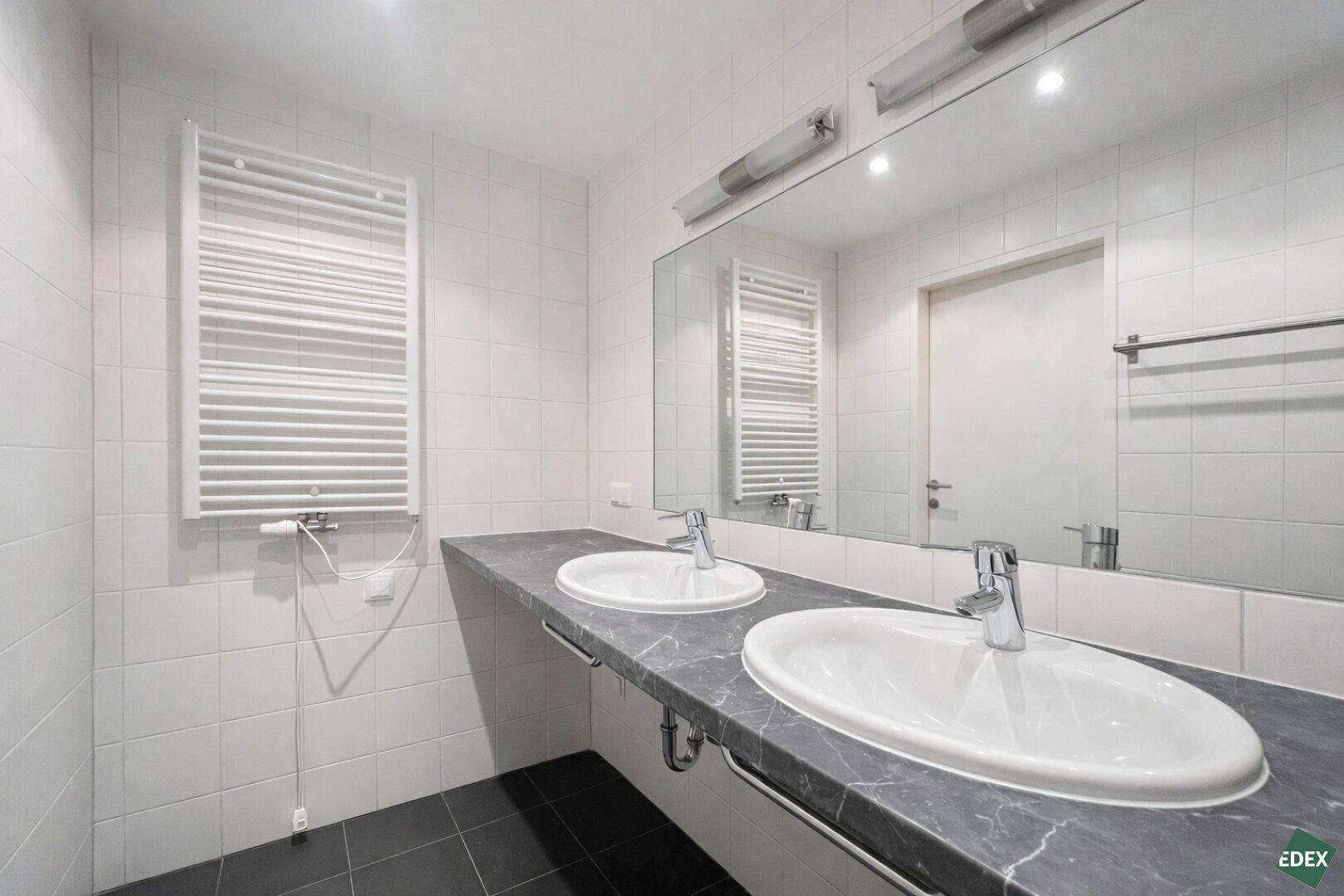 Modernes Badezimmer mit Doppelwaschbecken, großem Spiegel und beheiztem Handtuchhalter.