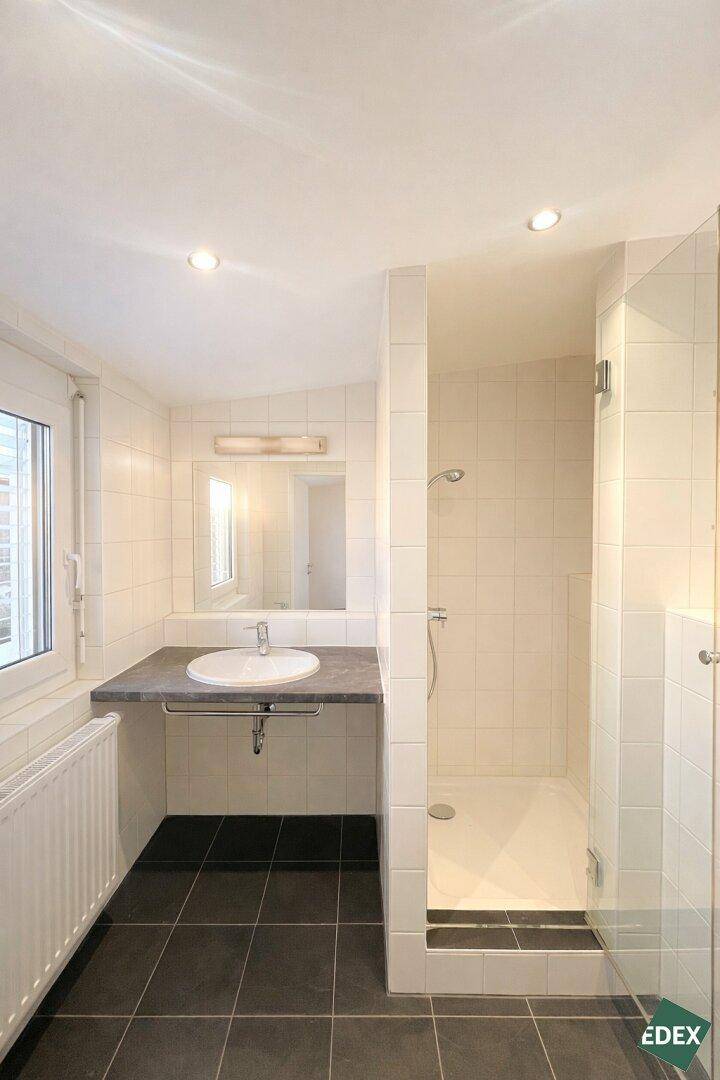 Modernes Badezimmer mit dunklen Fliesen, Einzelwaschbecken und einer begehbaren Dusche.