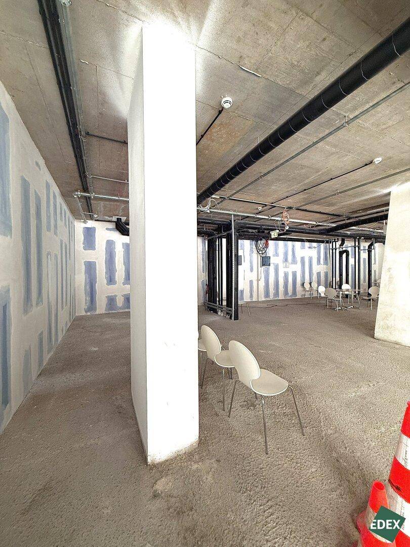 Unfertiger Gewerberaum mit einer markanten weißen Säule, Betonboden und vorbereiteten Wänden für den weiteren Ausbau.