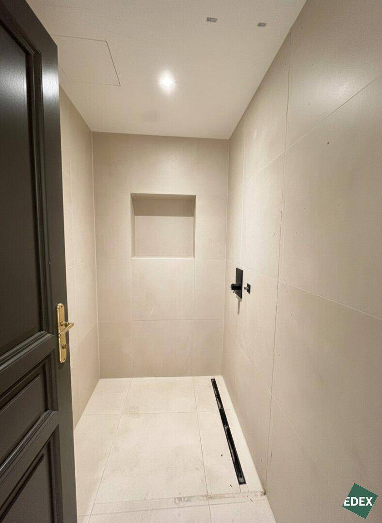 Modernes Badezimmer mit begehbarer Dusche, hellen Fliesen und einer praktischen Nische in der Wand.