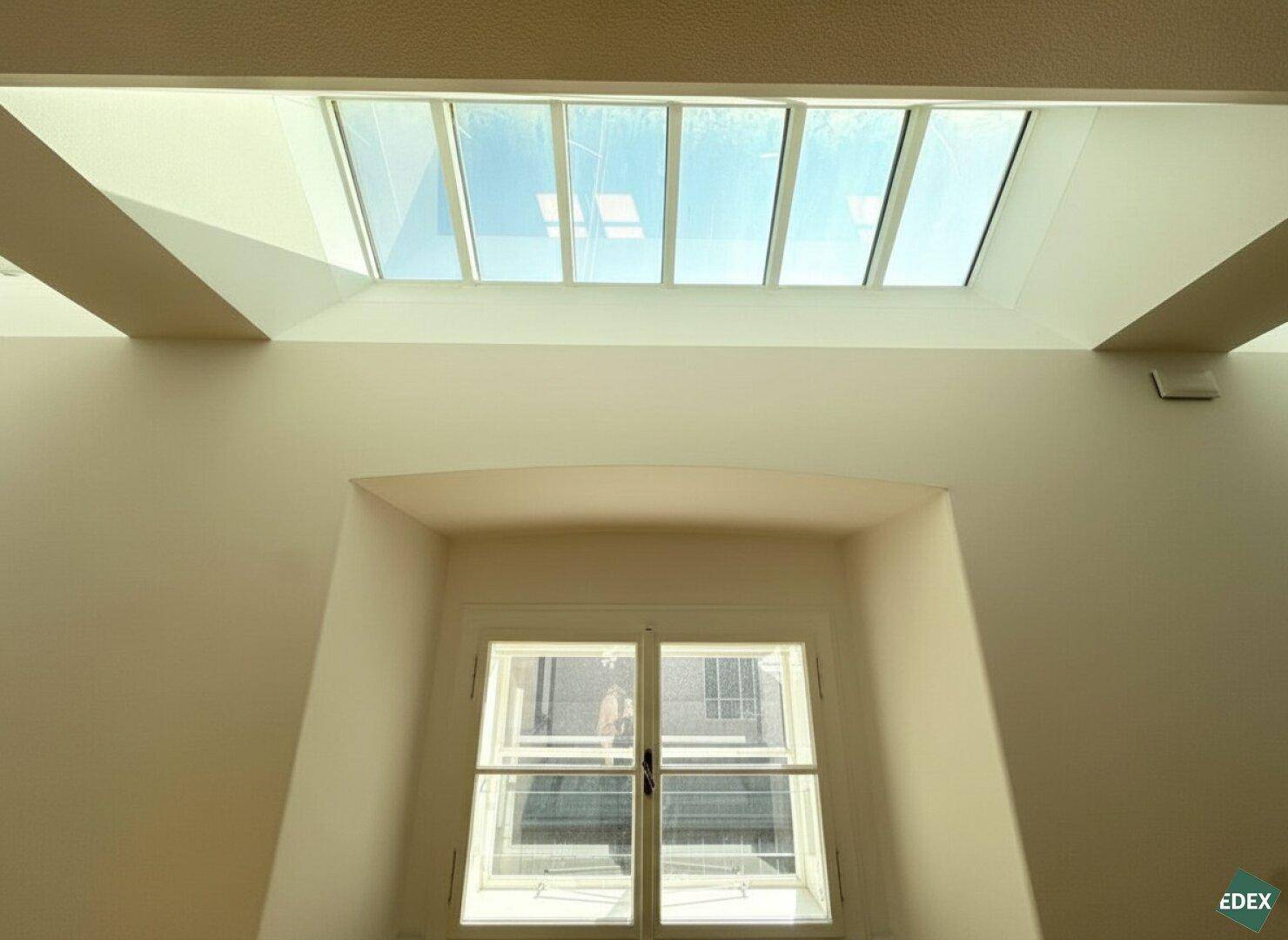 Fenster mit Blick nach draußen und ein großes Oberlicht, das den Raum mit natürlichem Licht durchflutet.