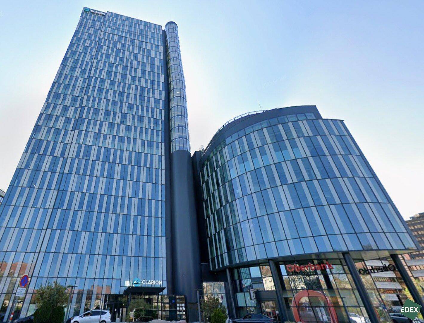 Beeindruckendes modernes Hochhaus mit blauer Glasfassade und geschwungenen Formen, das eine markante Architektur zeigt.