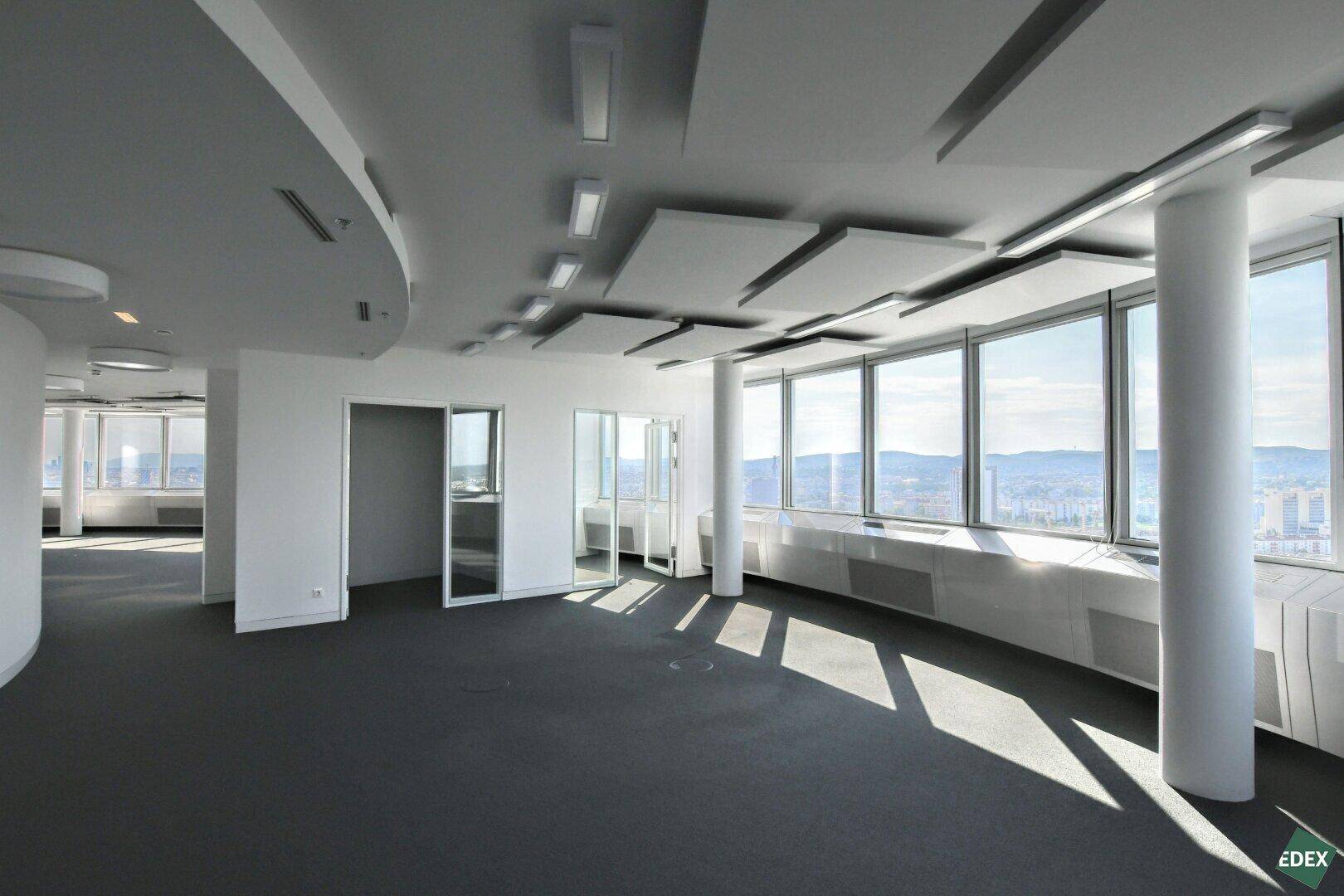 Großzügiger Bürobereich mit Glaszugang zu weiteren Räumen, großen Fenstern und weitem Stadtpanorama.