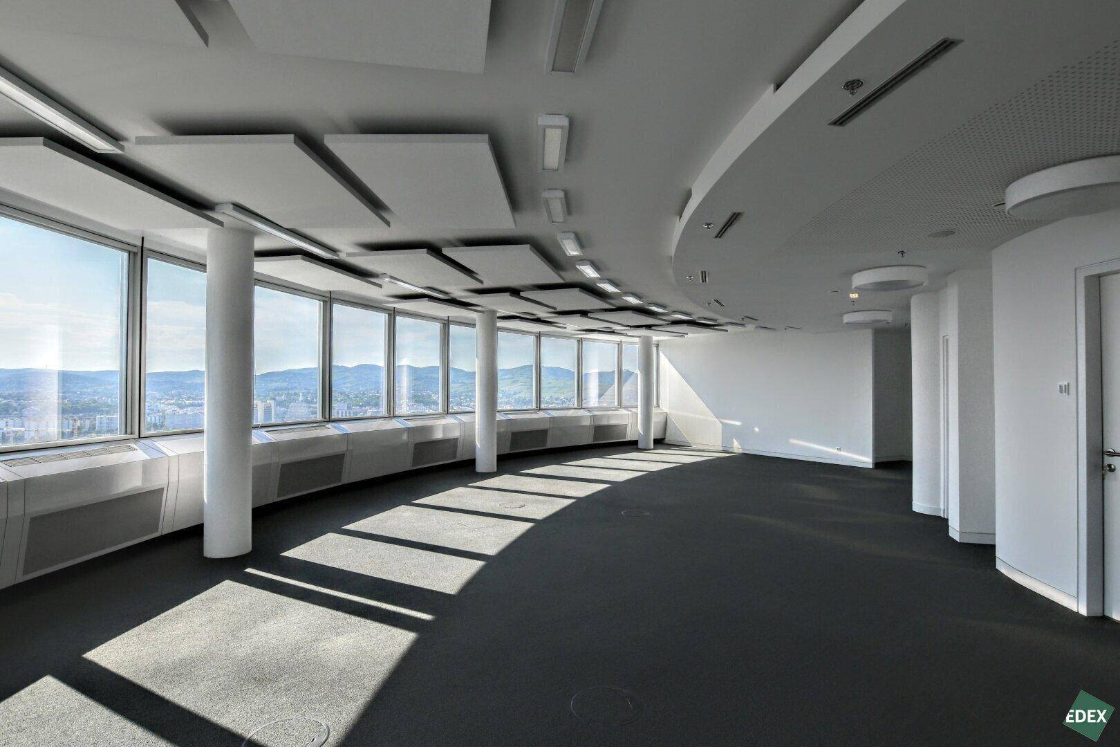 Heller Bürobereich mit geschwungener Architektur, großen Fenstern und beeindruckendem Ausblick über die Stadt.
