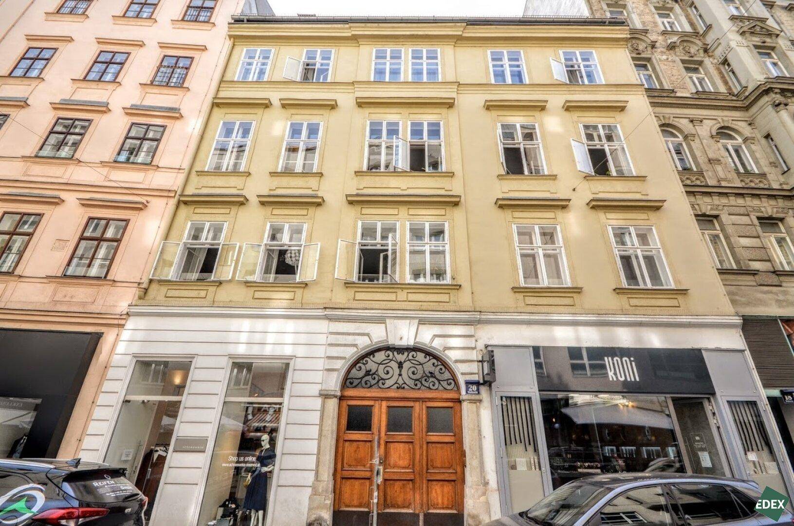 Historisches Gebäude mit klassischer Fassade und großen Fenstern in einer städtischen Umgebung.