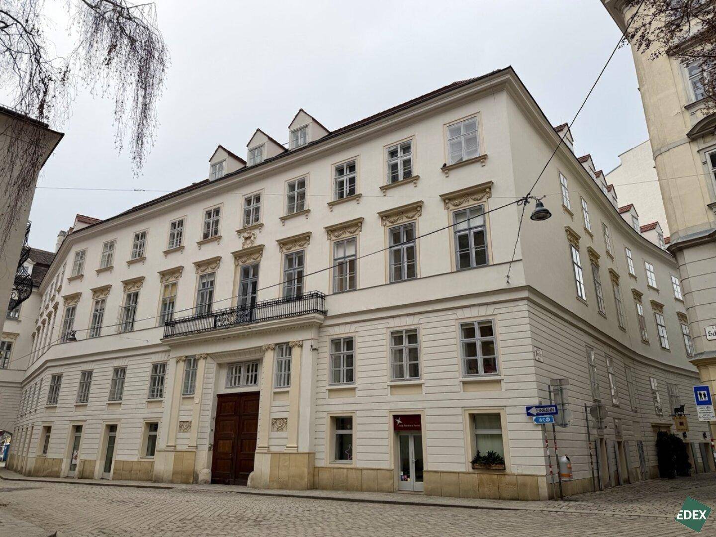 Großes, helles Eckgebäude mit klassischer Architektur, vielen Fenstern und einem prominenten Eingangsbereich.