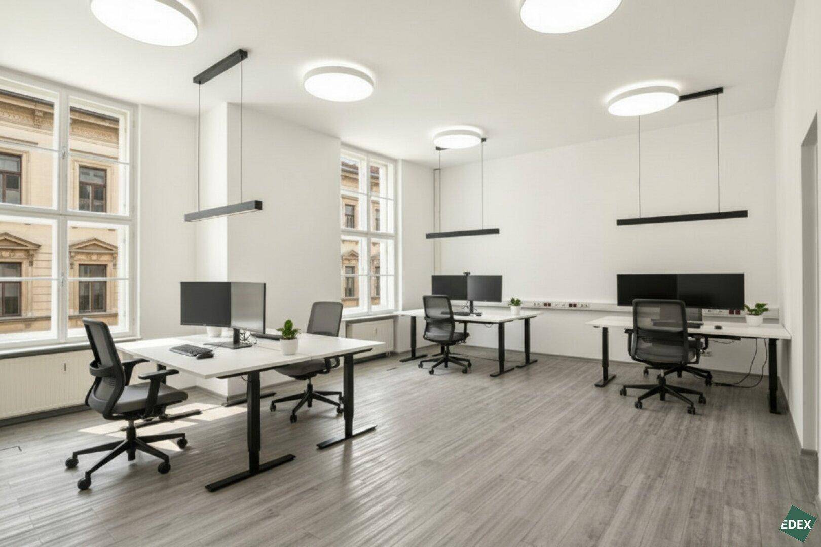 Modern eingerichtetes Büro mit mehreren Arbeitsplätzen, großen Fenstern und zeitgemäßer Deckenbeleuchtung.