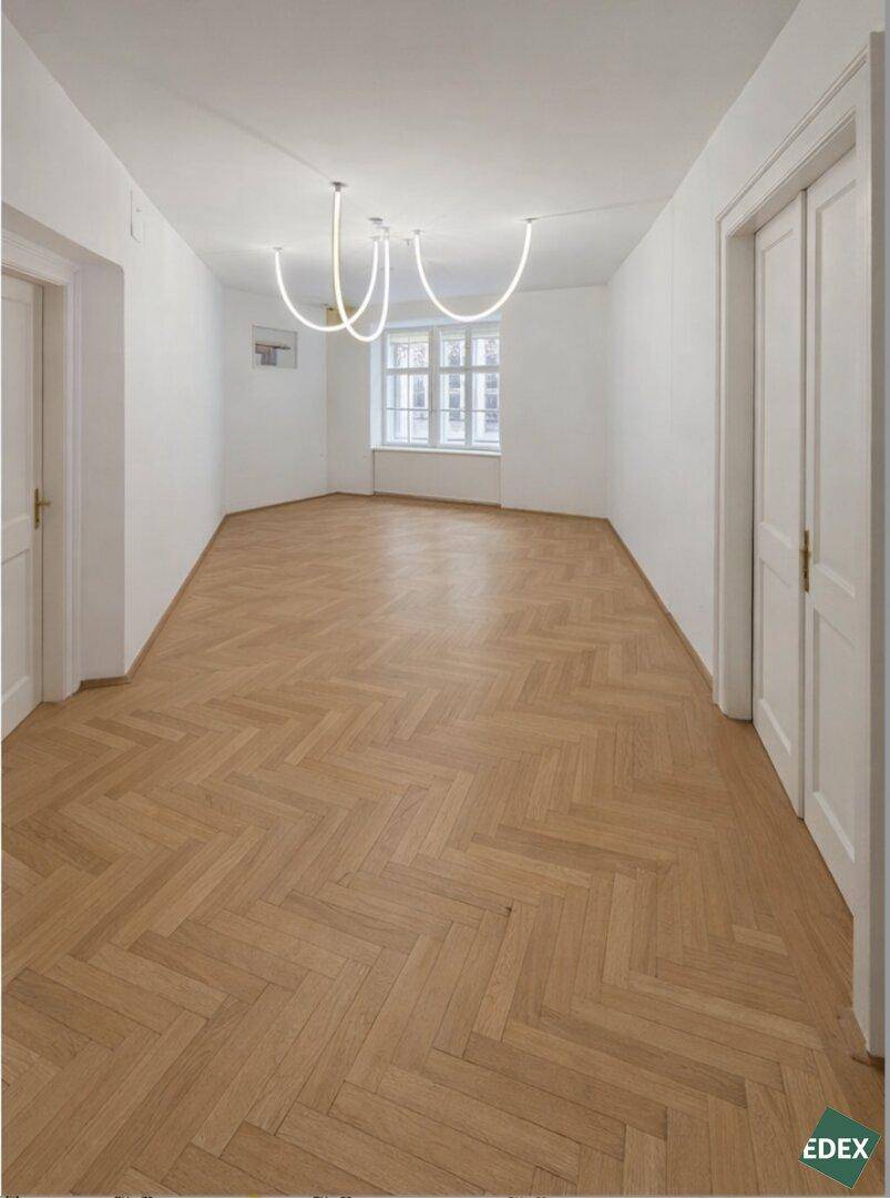 Heller Raum mit elegantem Fischgrätparkett, einem Erkerfenster und einer modernen Deckenleuchte.