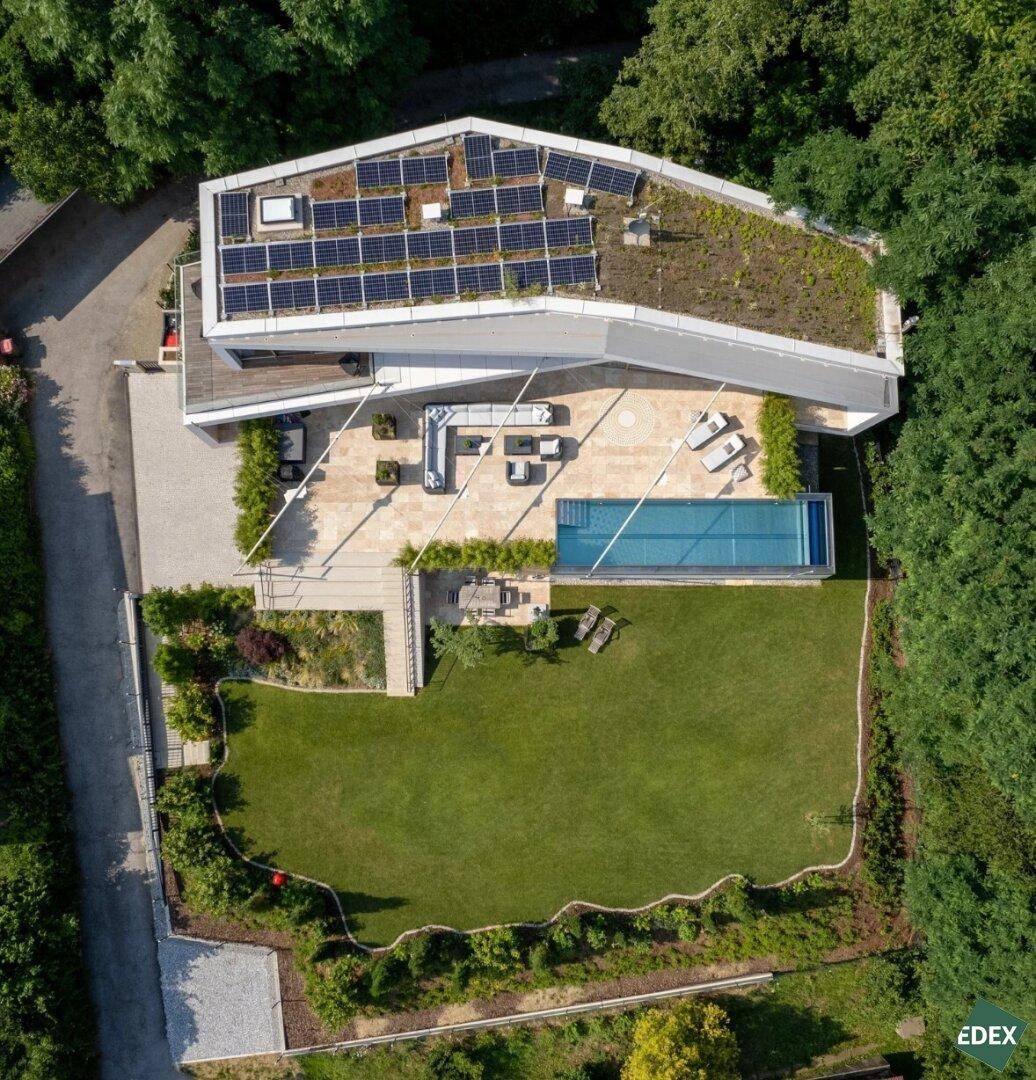 Luftaufnahme der modernen Villa mit Pool, großer Terrasse, Solaranlage und Gründach.