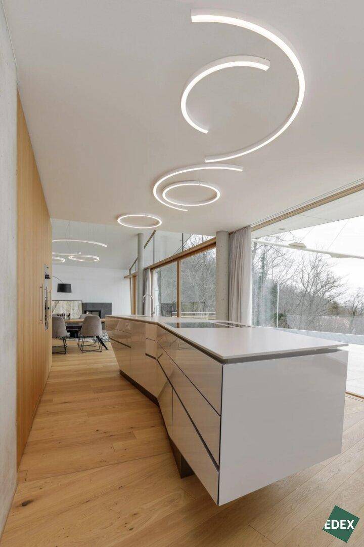 Moderne offene Küche mit weißer Kücheninsel, Holzfußboden und großen Fensterfronten.