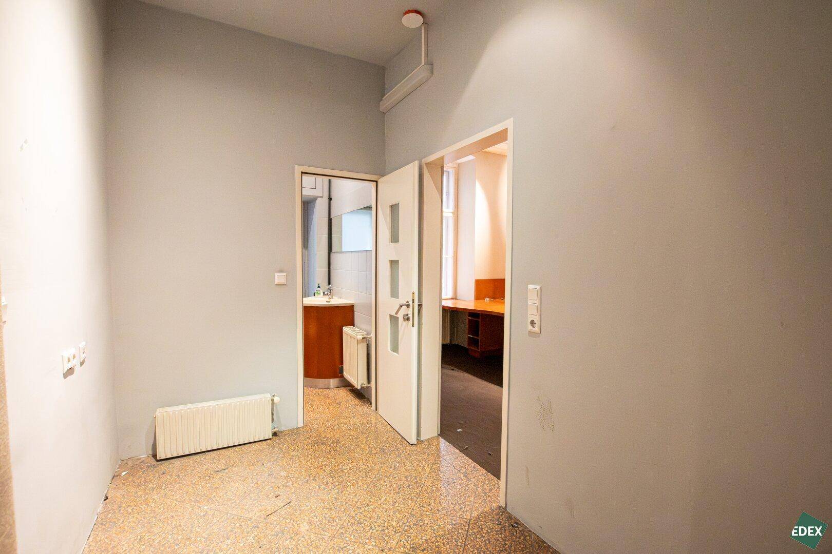 Flur mit Zugang zu weiteren Räumen und einem Badezimmer, ausgestattet mit Heizkörper und Klimaanlage.