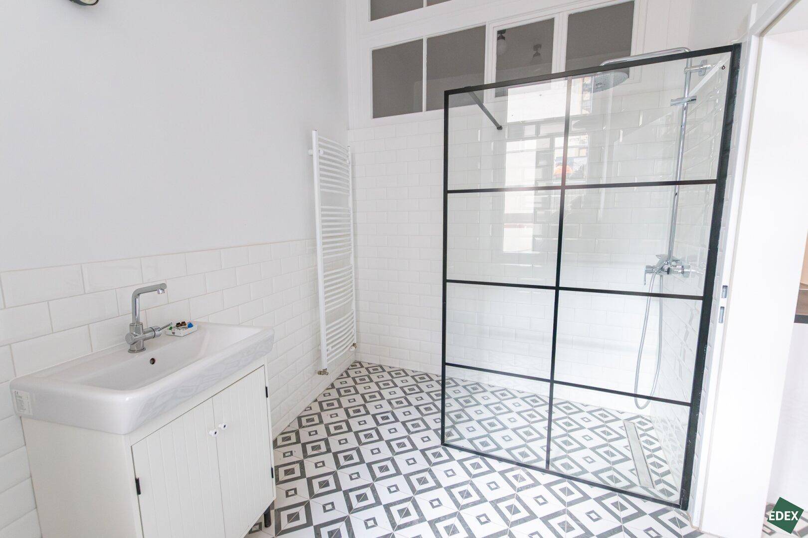Modernes Badezimmer mit begehbarer Dusche, weißer Metrofliesenwand und gemustertem Boden.