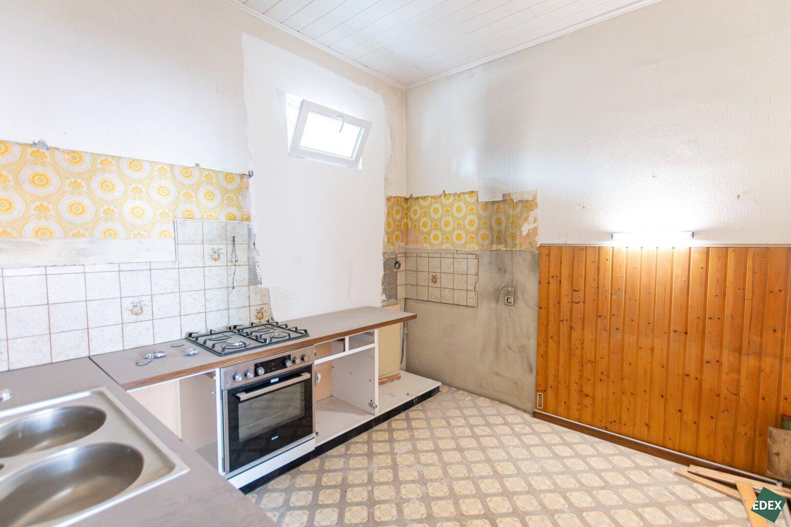 Renovierungsbedürftige Küche mit Gasherd, Backofen und Dachfenster, bereit zur Modernisierung.