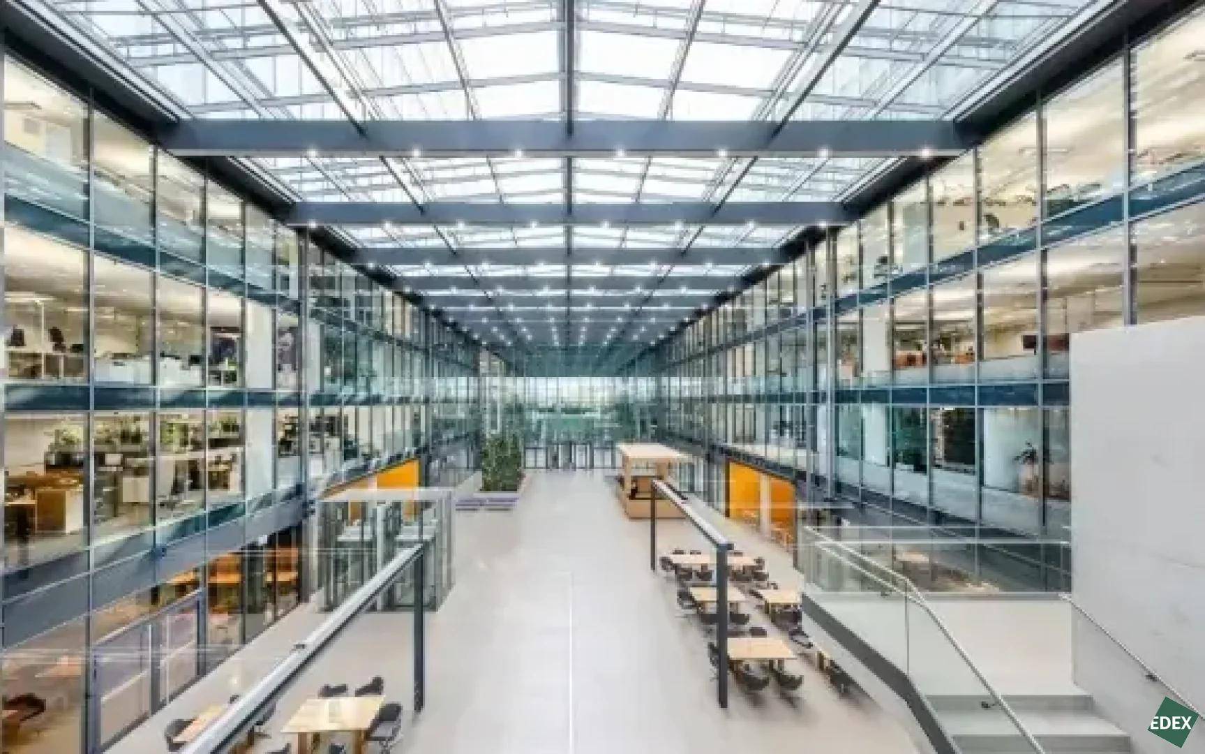 Weitläufiges Atrium mit beeindruckender Glasarchitektur, natürlicher Beleuchtung und offenen Büroflächen auf mehreren Ebenen.