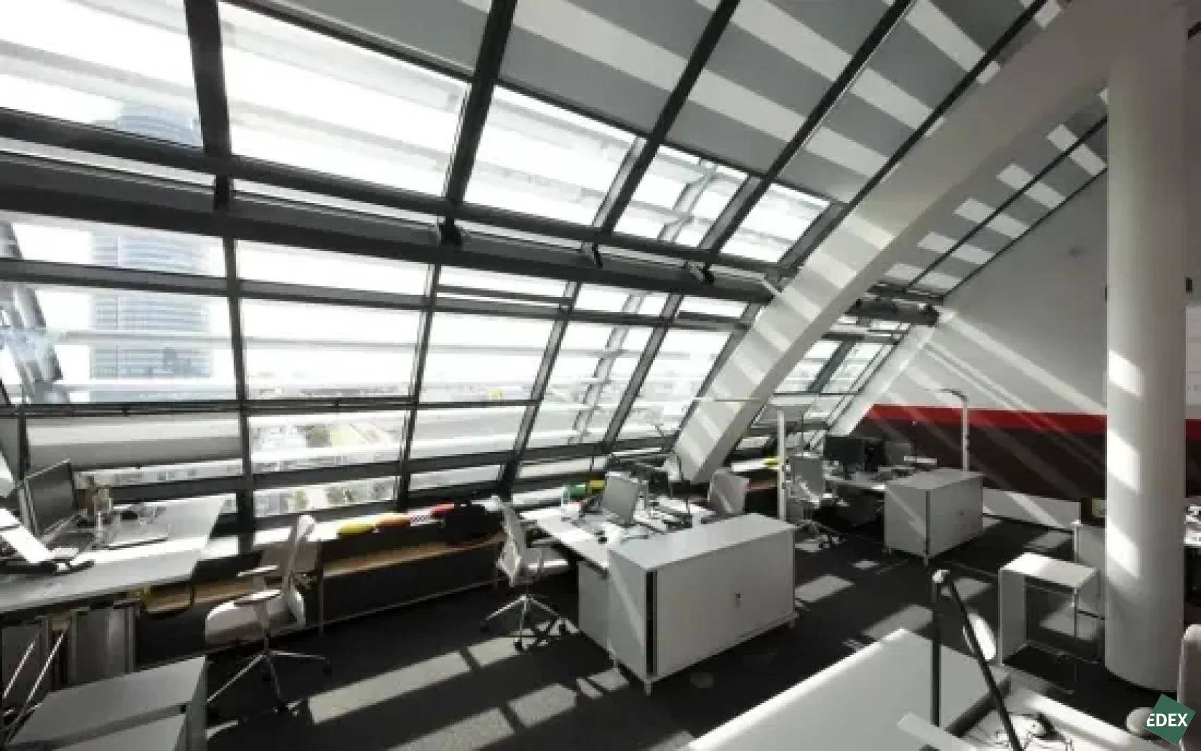 Modernes Büro im Dachgeschoss mit schrägen Glasfenstern und viel Tageslicht für mehrere Arbeitsplätze.