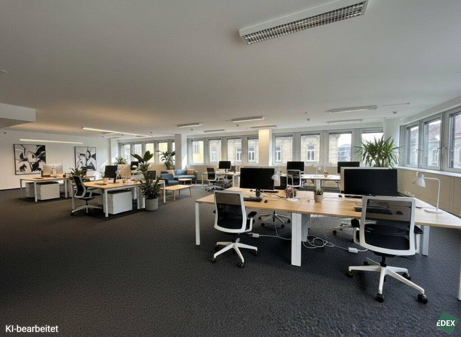 Großer, modern ausgestatteter Bürobereich mit mehreren Arbeitsplätzen und Pflanzen, die für eine angenehme Atmosphäre sorgen.