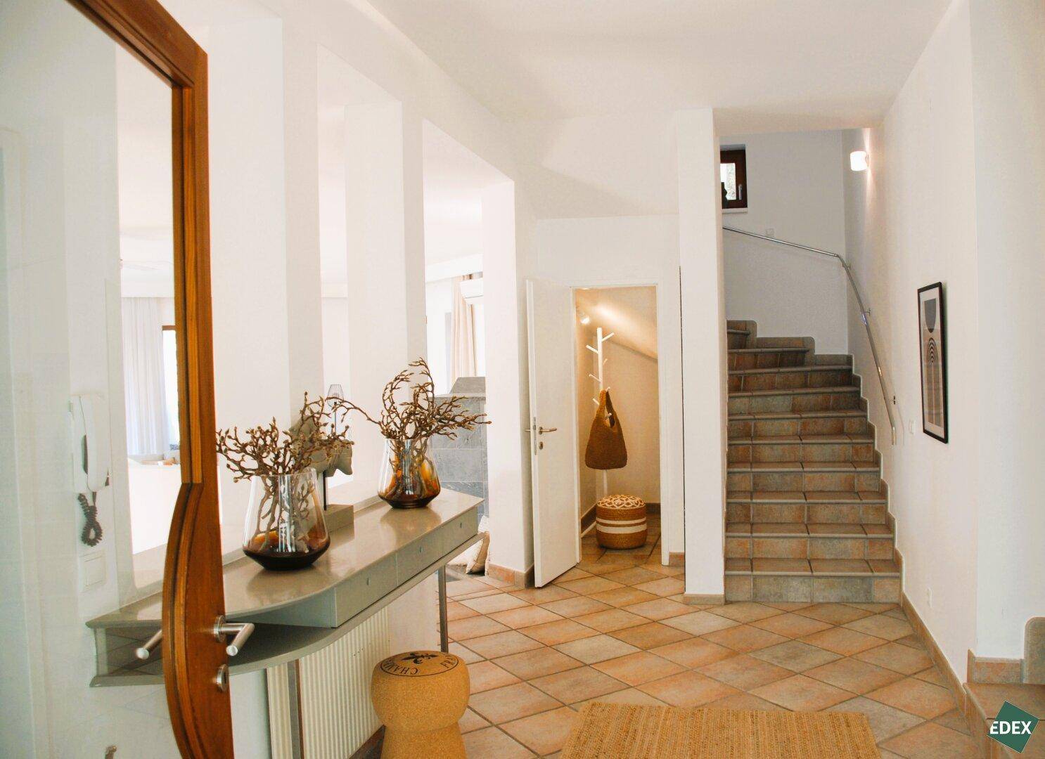 Heller Eingangsbereich mit Terrakotta-Fliesenboden und Treppe zum Obergeschoss.