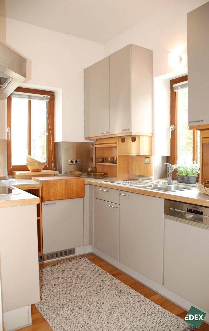 Helle Einbauküche mit modernen Geräten, Holzdetails und Fenster.