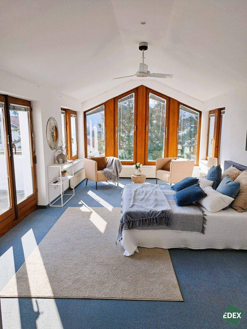 Helles Schlafzimmer mit großen Fenstern, Dachschräge und Zugang zum Balkon.