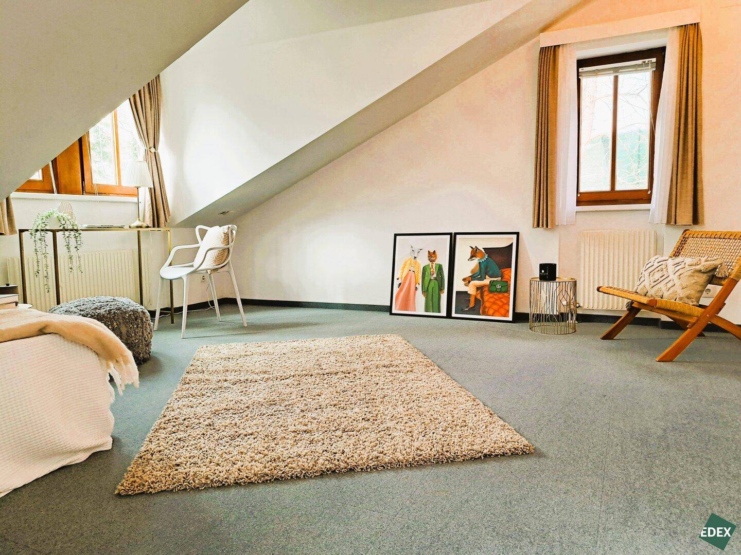Gemütliches Schlafzimmer im Dachgeschoss mit Dachschrägen und Teppichboden.