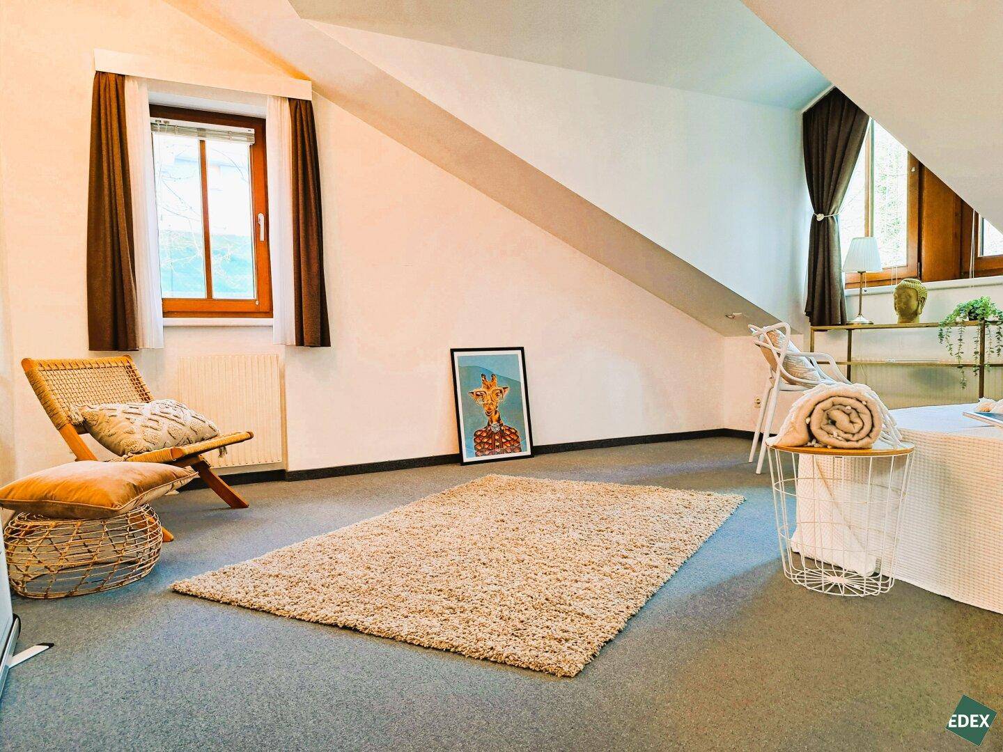Helles Dachgeschoss-Schlafzimmer mit schrägen Wänden und gemütlicher Einrichtung.