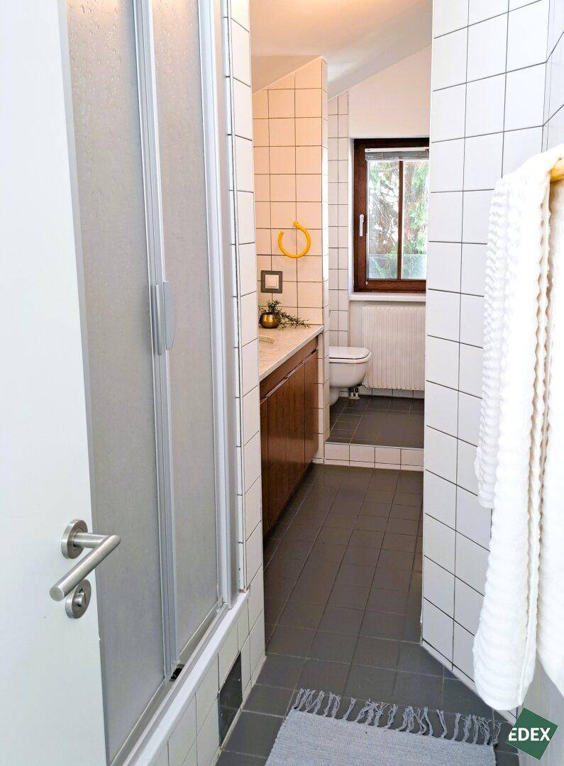 Funktionales Badezimmer mit Duschkabine, WC und Fenster.