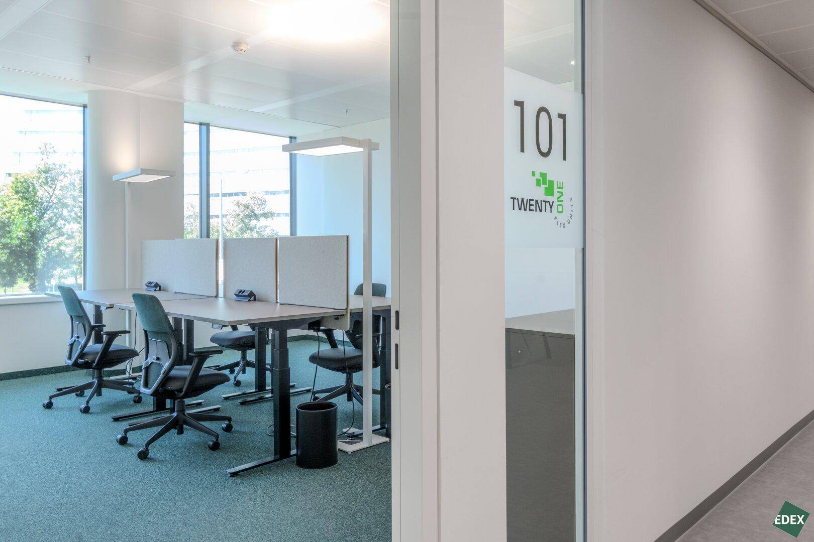 Helles Büro mit mehreren Arbeitsplätzen, großen Fenstern und Blick ins Grüne.