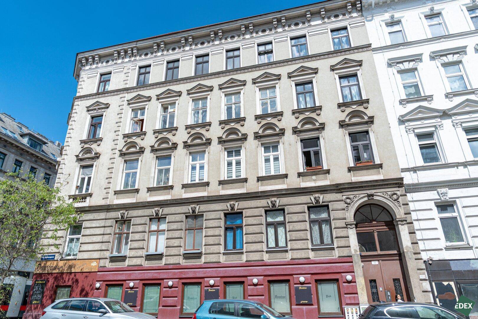 Historische Fassade eines Mehrfamilienhauses in der Stadt mit vielen Fenstern.