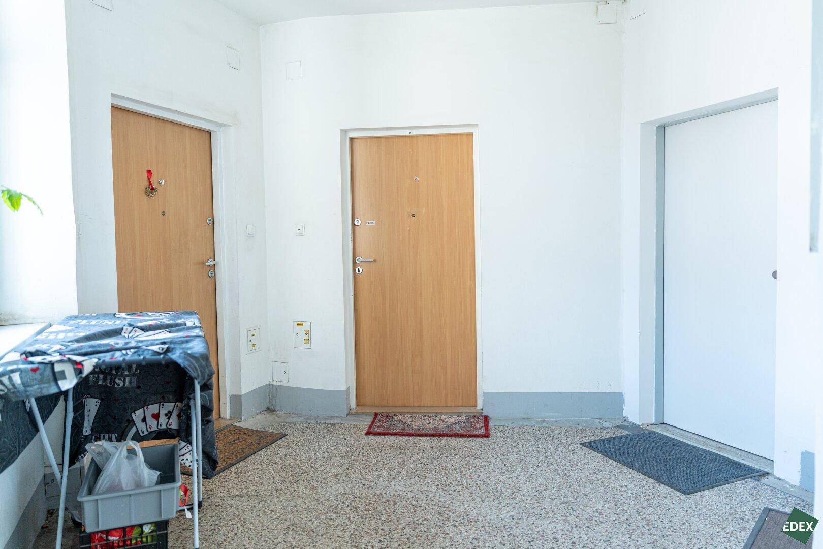 Eingangsbereich mit mehreren Holztüren und einem Terrazzoboden, der zu den Wohnungen führt.