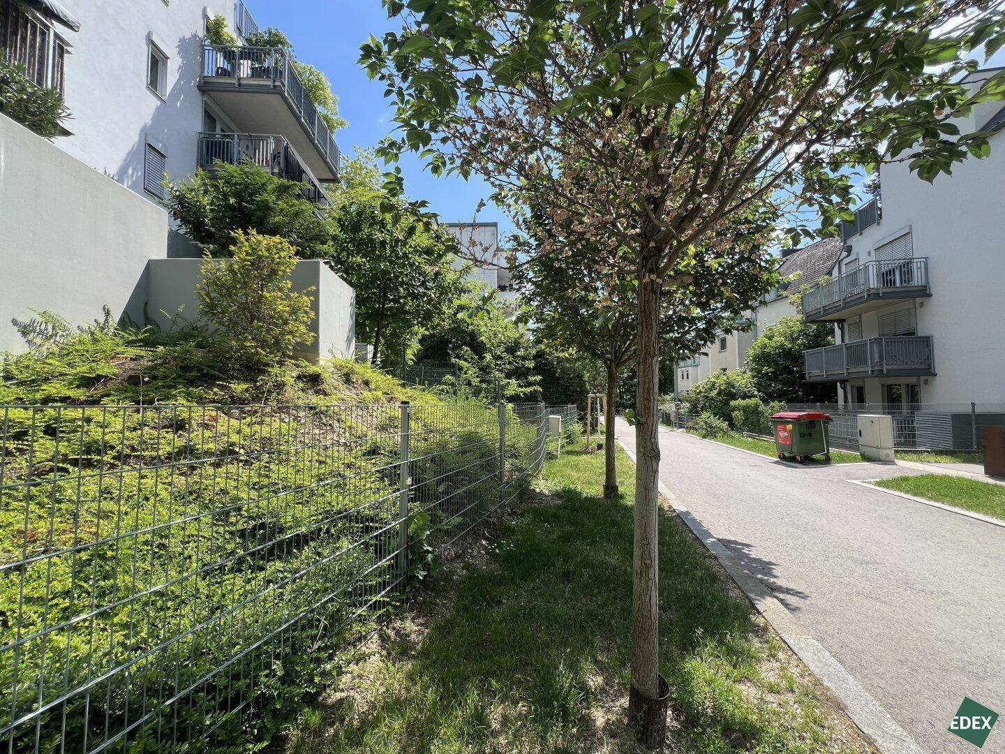 Ansicht der Wohnanlage von der Straße aus, umgeben von Bäumen und gepflegten Grünflächen.