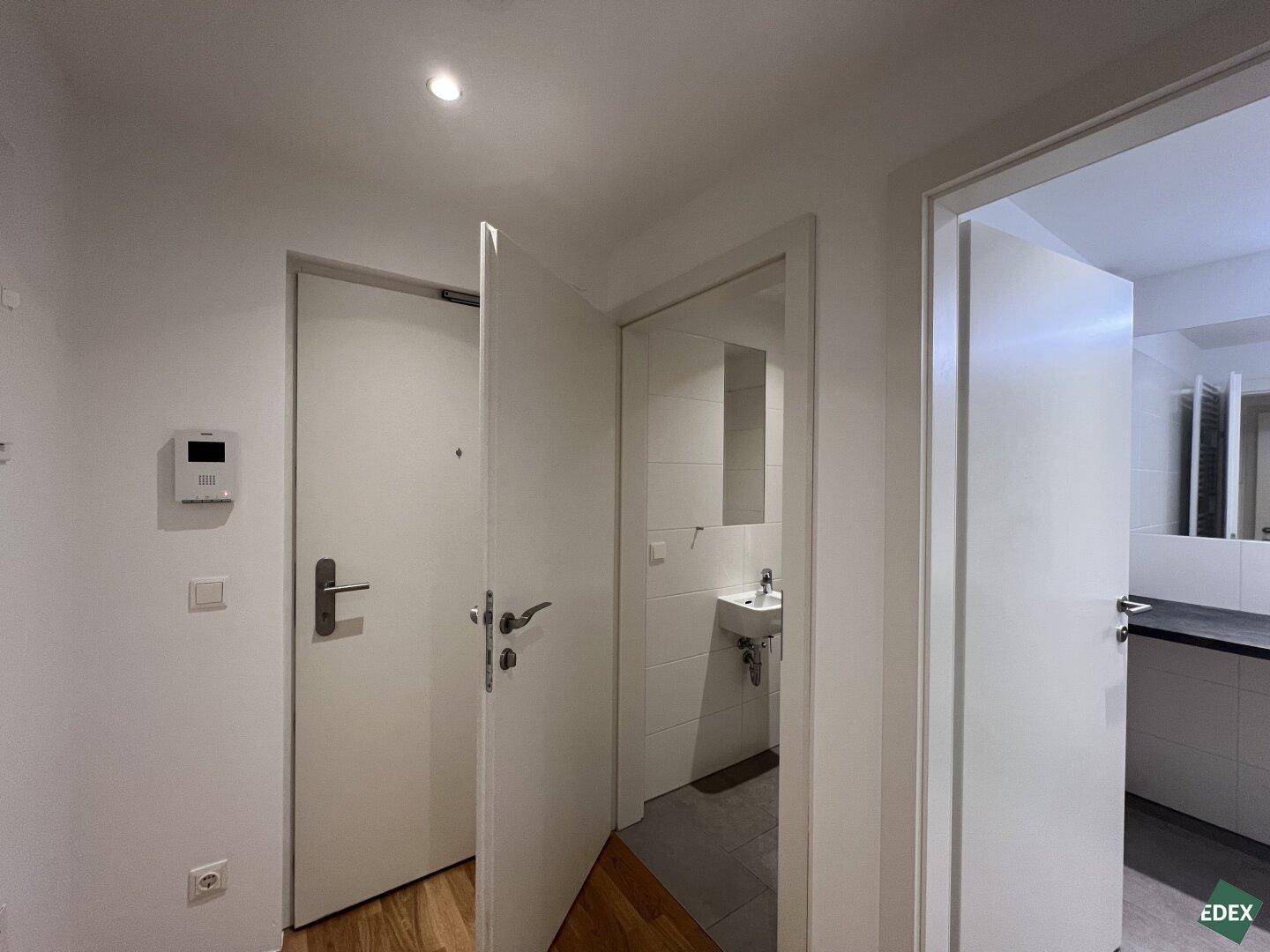 Flur mit Zugang zur Gästetoilette und weiteren Räumen, hell und funktional gestaltet.