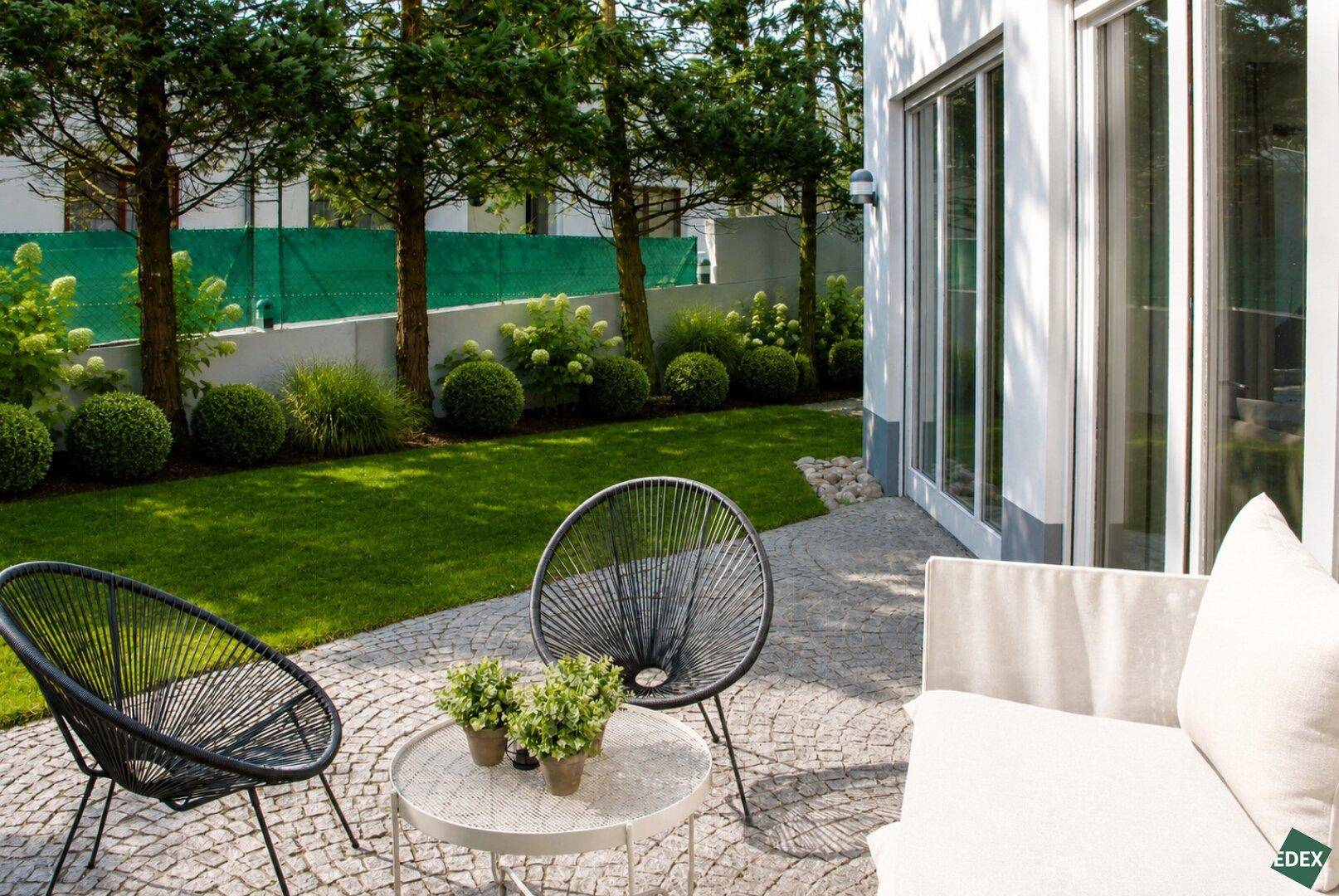 Gemütliche Terrasse mit modernen Gartenmöbeln und Blick auf den grünen Garten.