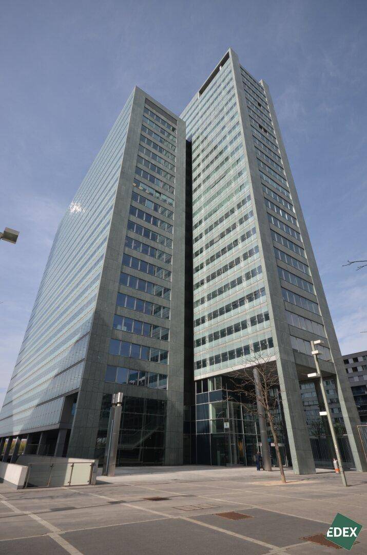 Beeindruckendes modernes Hochhaus mit einer eleganten Glasfassade unter blauem Himmel.
