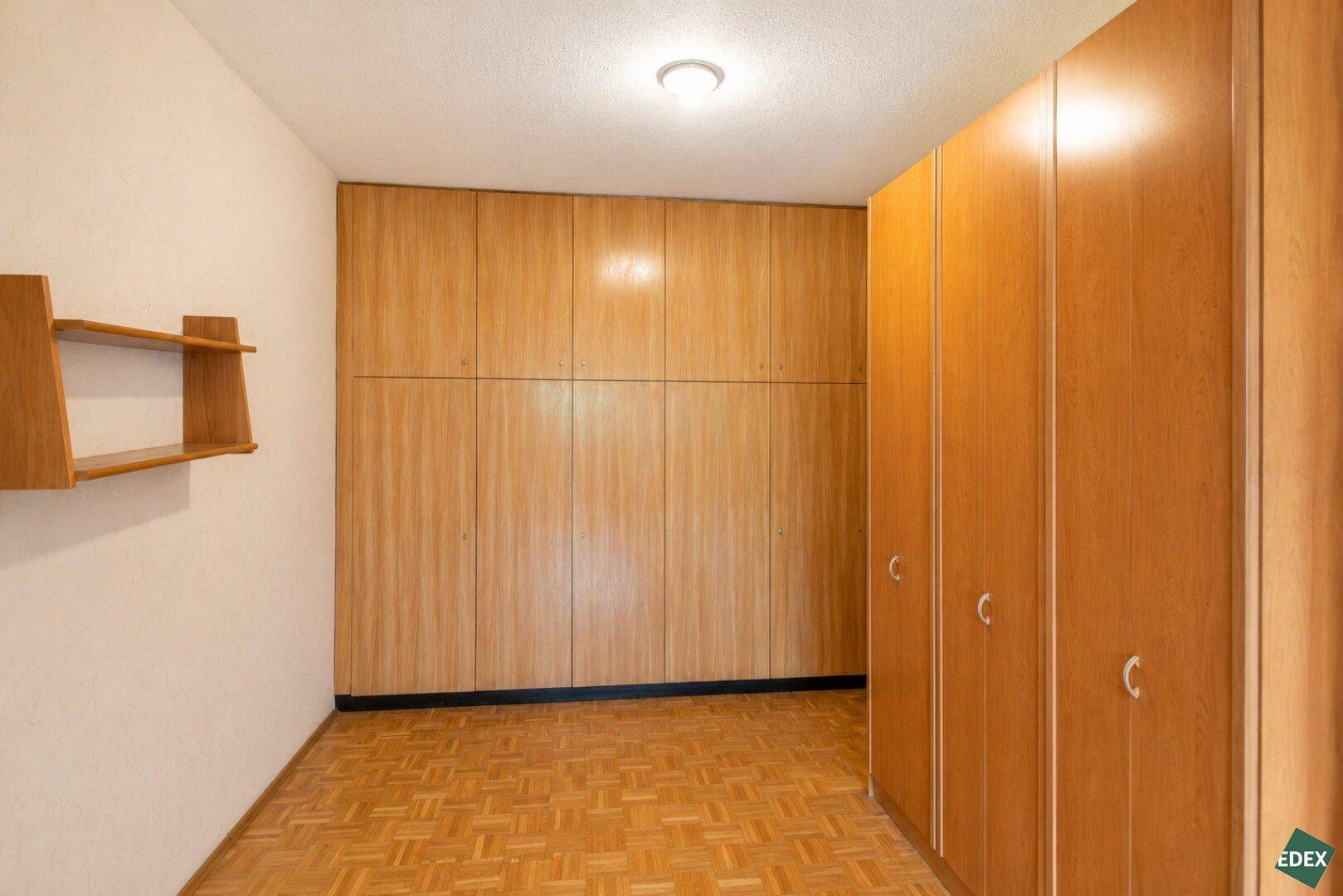 Schlafzimmer mit Parkettboden und großen Einbauschränken aus Holz.