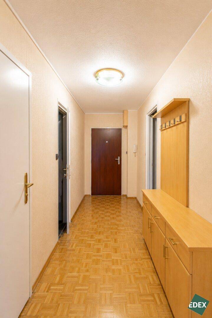 Heller Flur mit Parkettboden, Garderobe und Zugang zu verschiedenen Räumen.