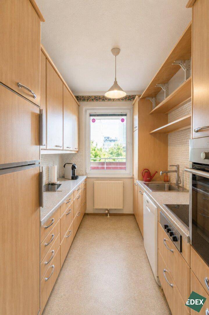 Helle Küche mit Holzfronten, modernen Geräten und einem Fenster für Tageslicht.