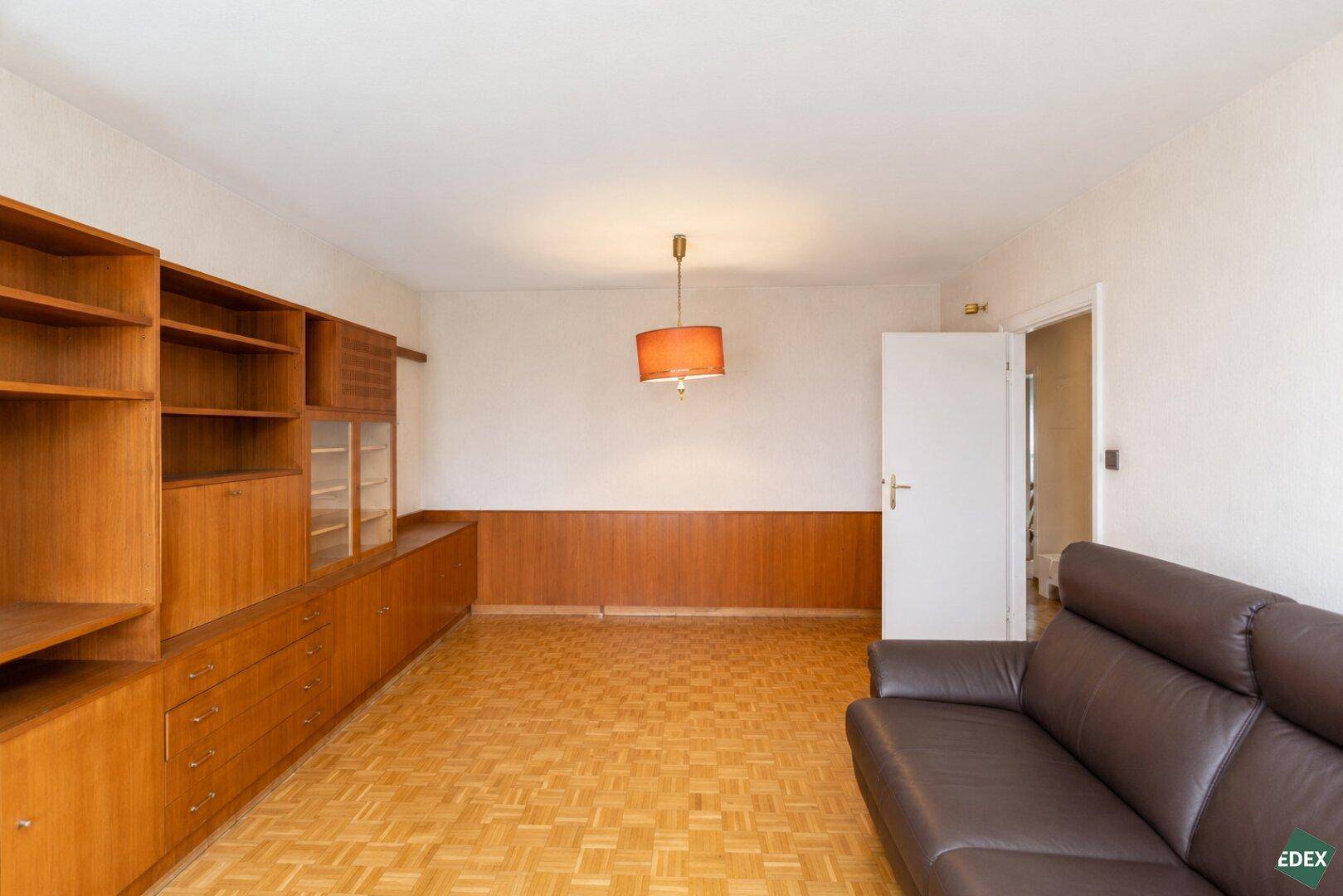 Wohnzimmer mit Parkettboden, Holzvertäfelung und einem bequemen Ledersofa.
