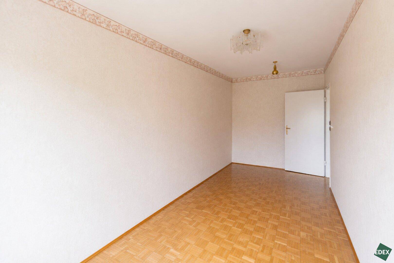 Leeres Schlafzimmer mit Parkettboden und weiß gestrichenen Wänden, bereit zur Einrichtung.