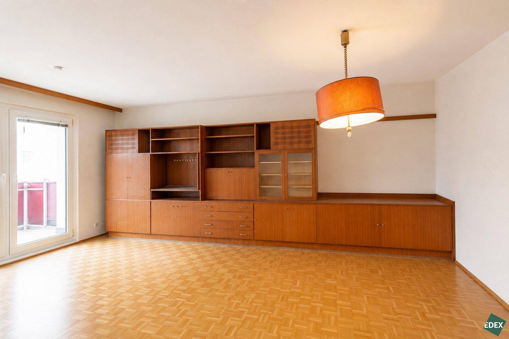 Wohnzimmer mit Parkettboden und einer großen, integrierten Holzschrankwand.