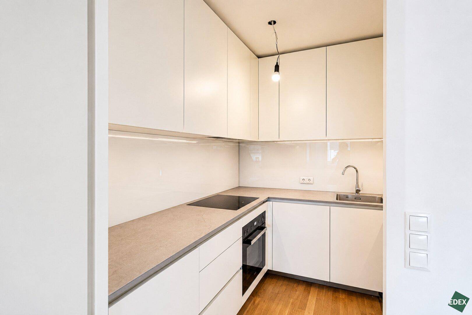 Moderne Einbauküche mit weißen Schränken, Spüle und Induktionskochfeld.