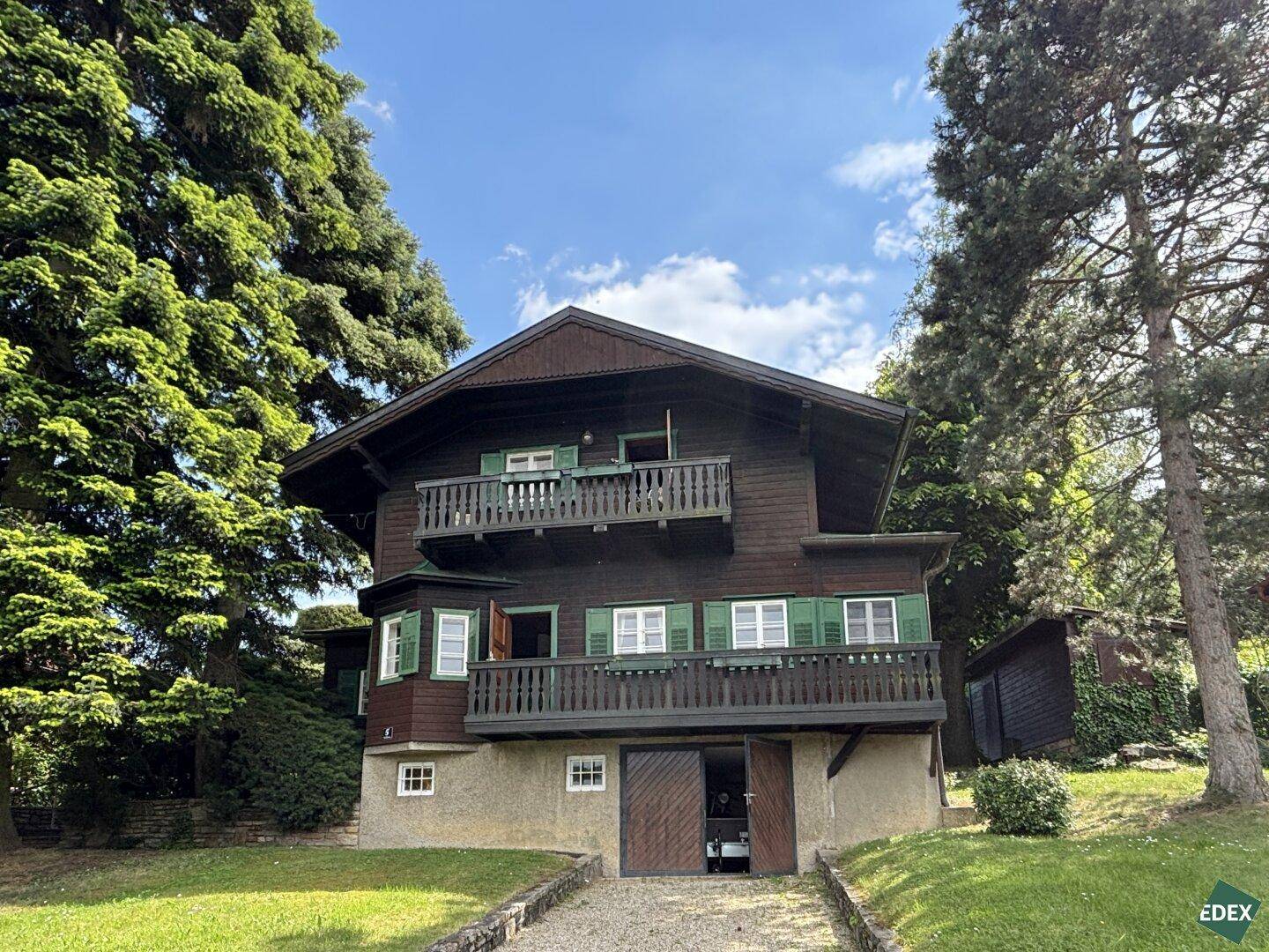 Traditionelles Holzhaus im Chalet-Stil mit mehreren Balkonen und grünen Fensterläden.