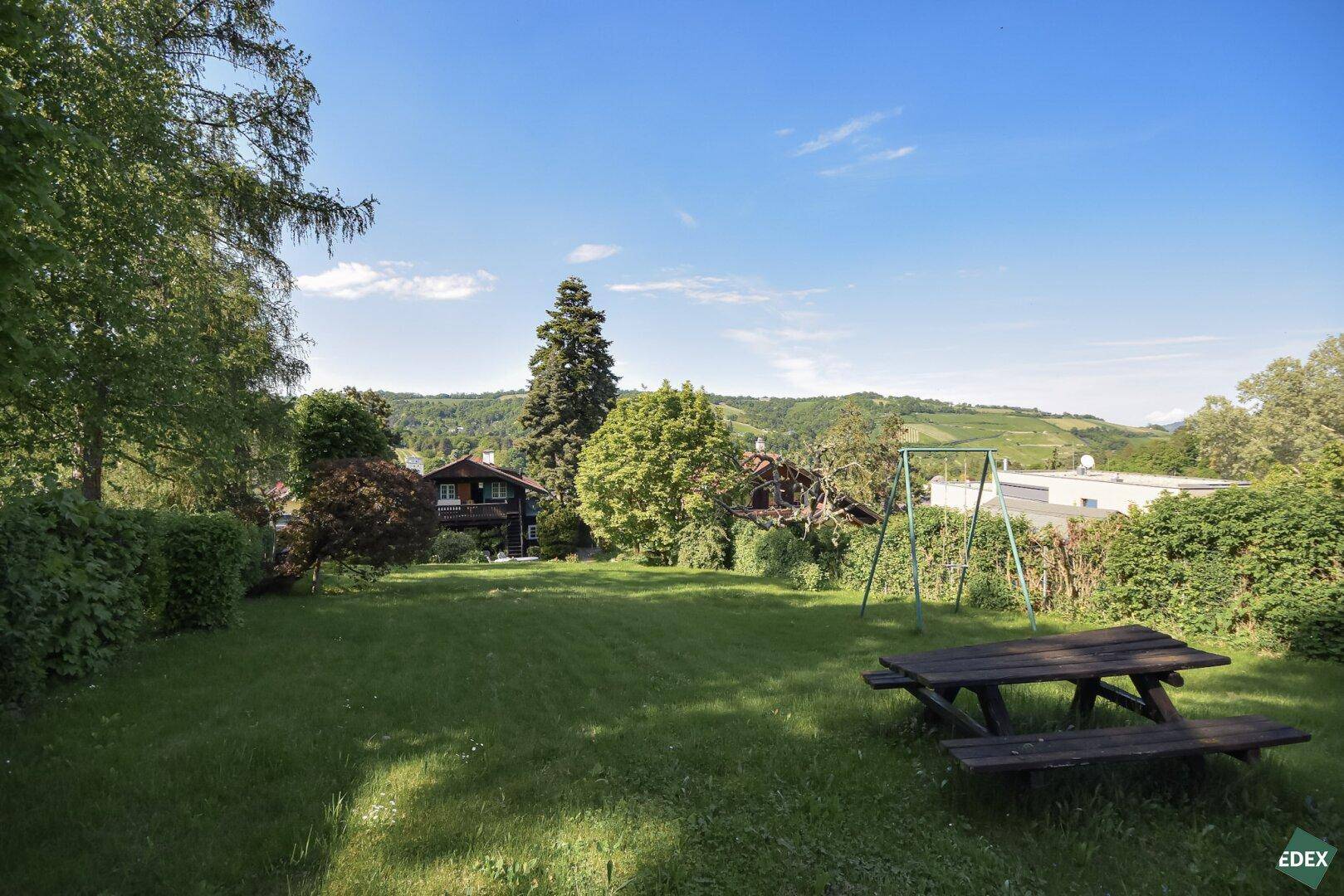 Großer Garten mit Picknicktisch, Schaukel und weitem Blick ins Grüne.
