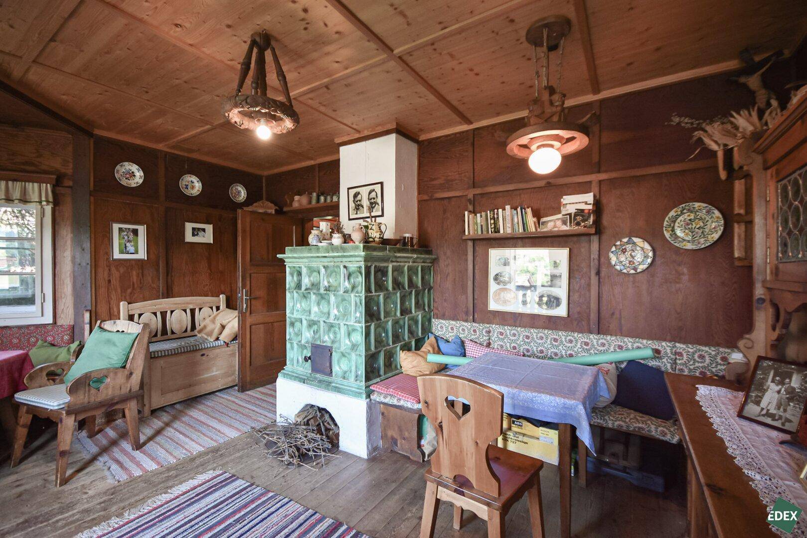Gemütliches Wohnzimmer im alpinen Stil mit Holztäfelung, Kachelofen und traditionellen Möbeln.