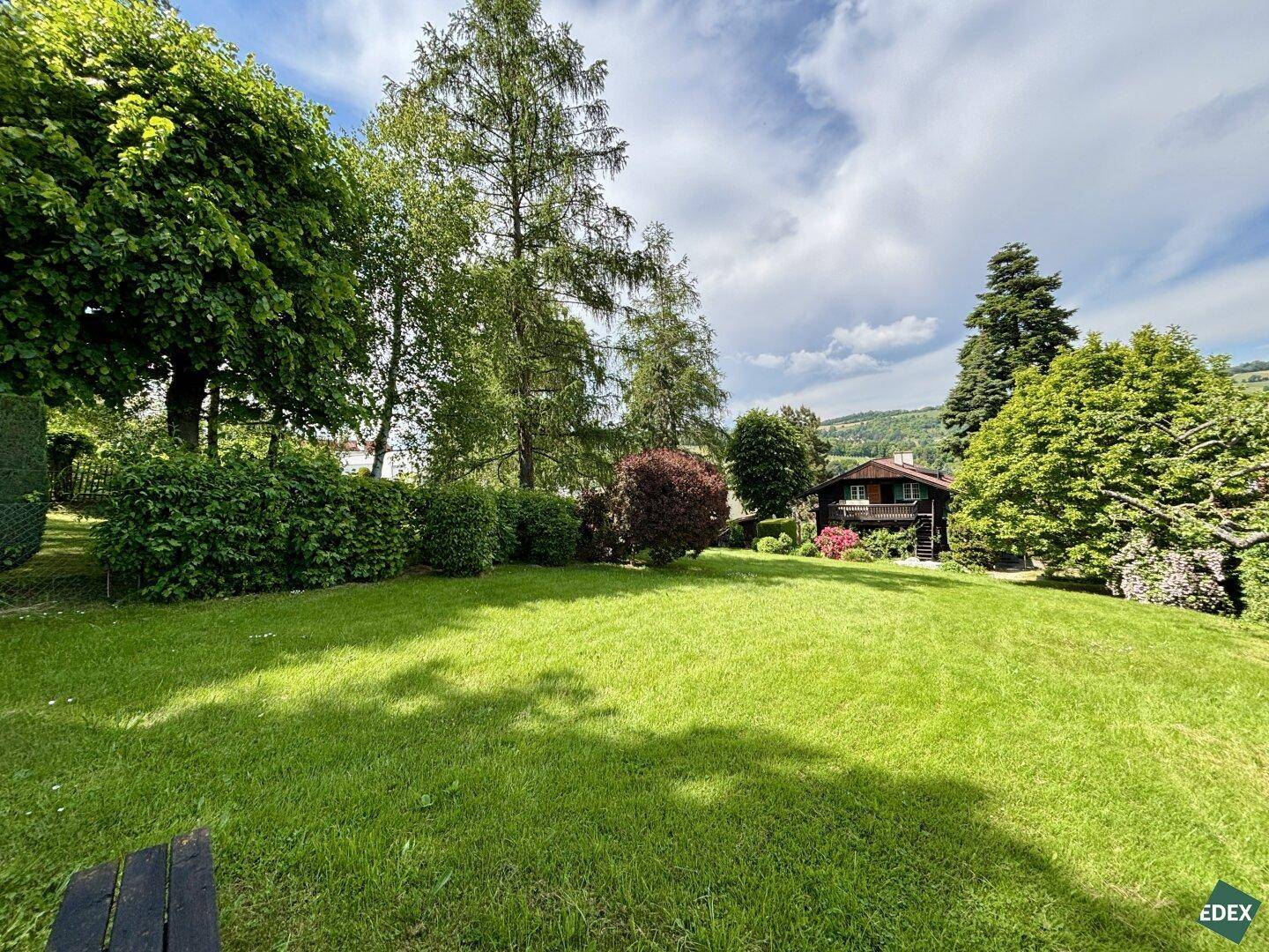 Weitläufiger Garten mit Rasenfläche, Picknicktisch und Blick auf die Umgebung.