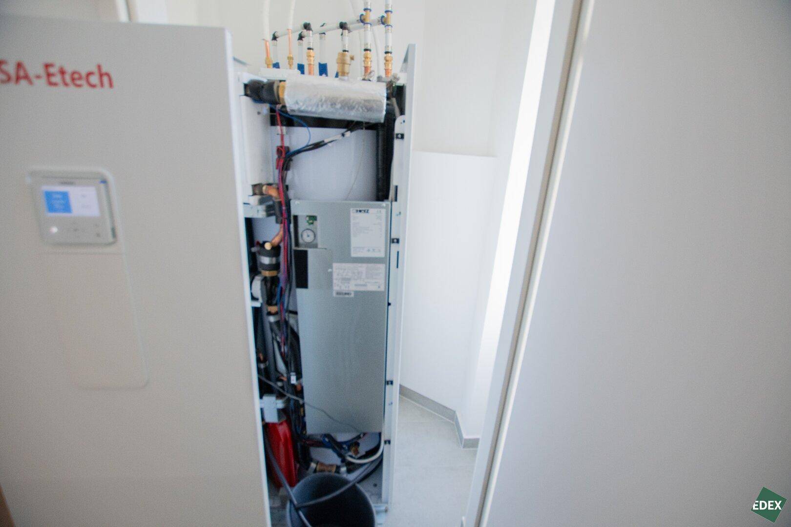 Detailansicht eines modernen Heizsystems mit sichtbaren Leitungen und Steuerungselementen in einem Technikraum.