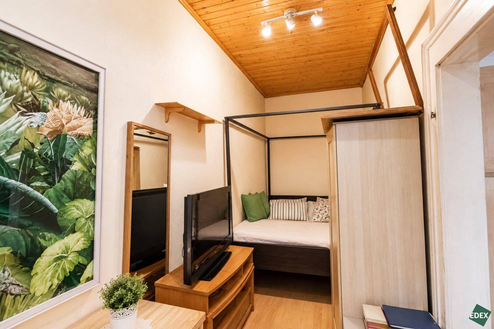 Kleines Schlafzimmer mit Holzbett, Holzdecke und einem Fernseher, optimiert für den Raum.