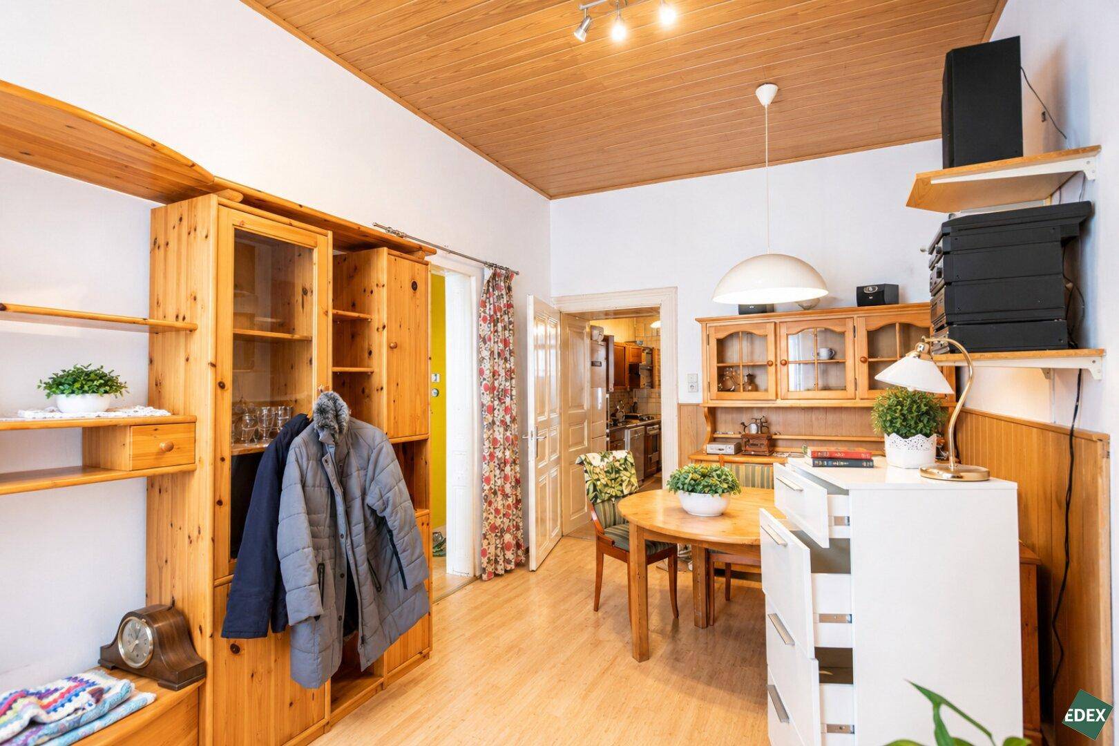 Kombinierter Wohn- und Essbereich mit Holzdecke, rundem Esstisch und traditionellen Möbeln.