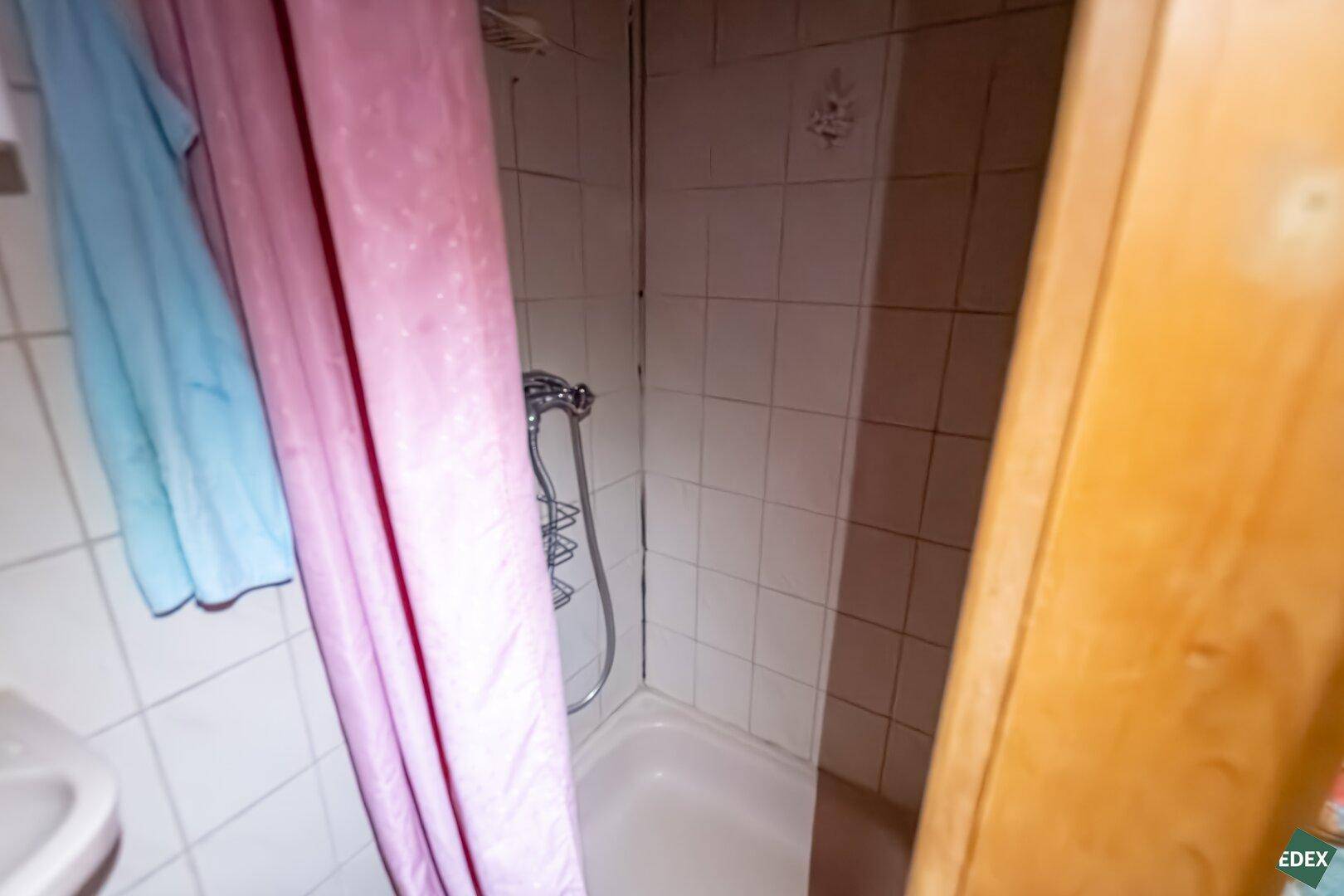 Einfaches Badezimmer mit Duschkabine und weißen Fliesen, funktional gestaltet.