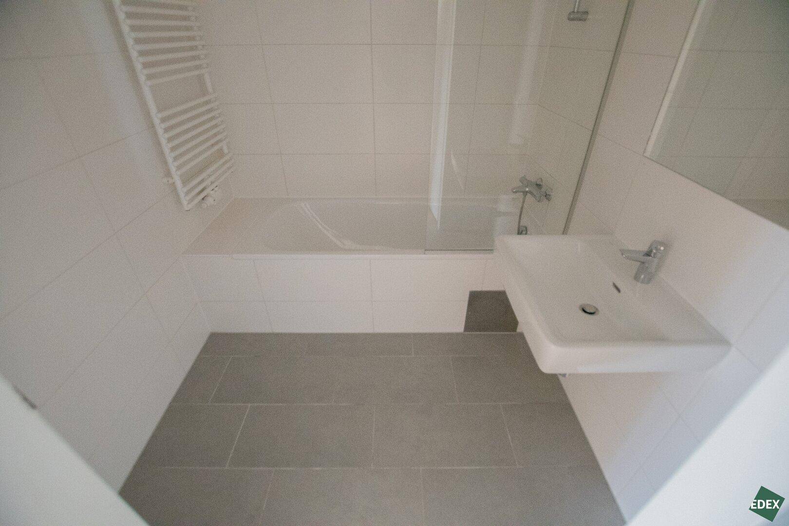 Modernes Badezimmer mit Badewanne, Waschbecken und beheiztem Handtuchhalter.